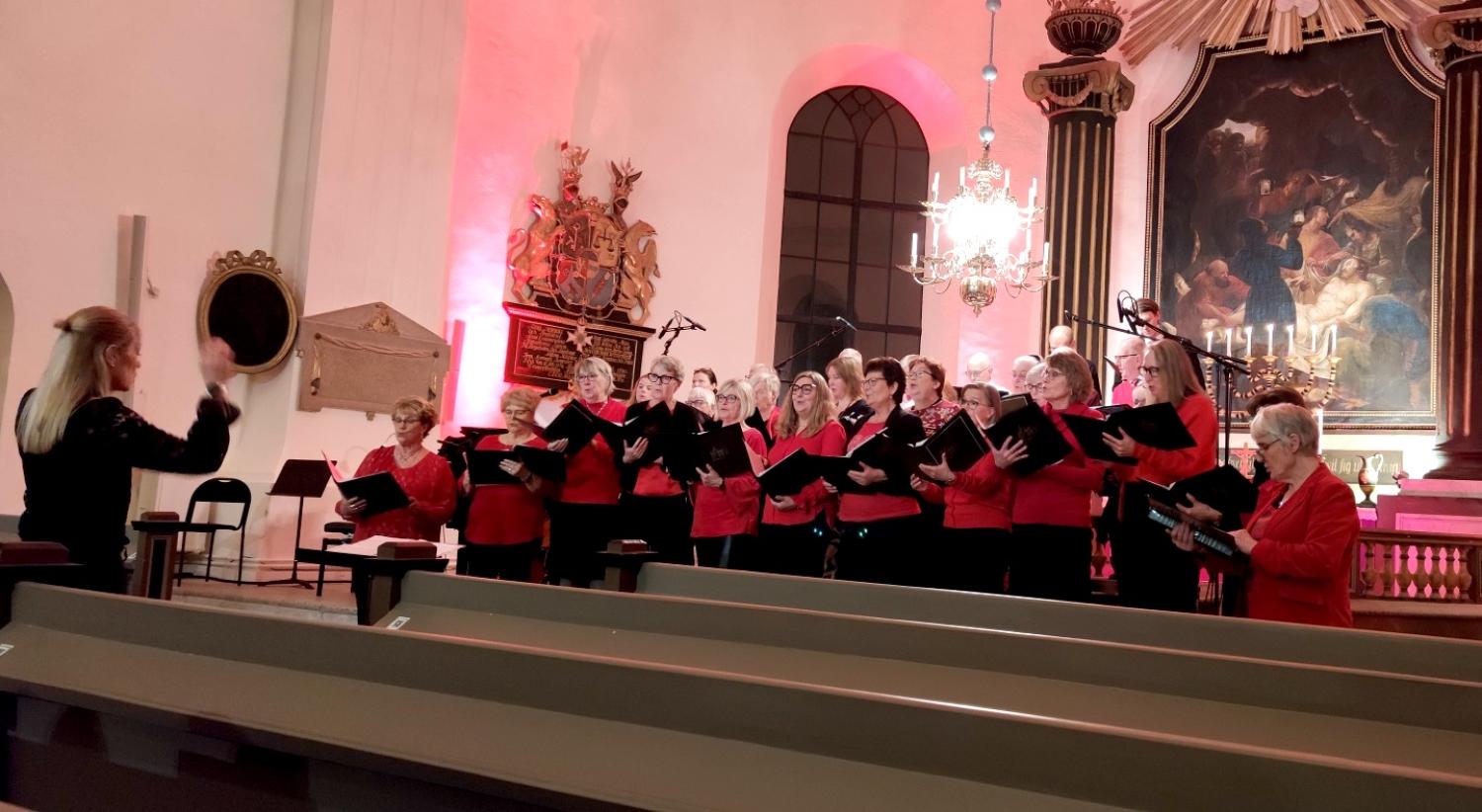 En grupp människor i röda skjortor sjunger i en kyrka.