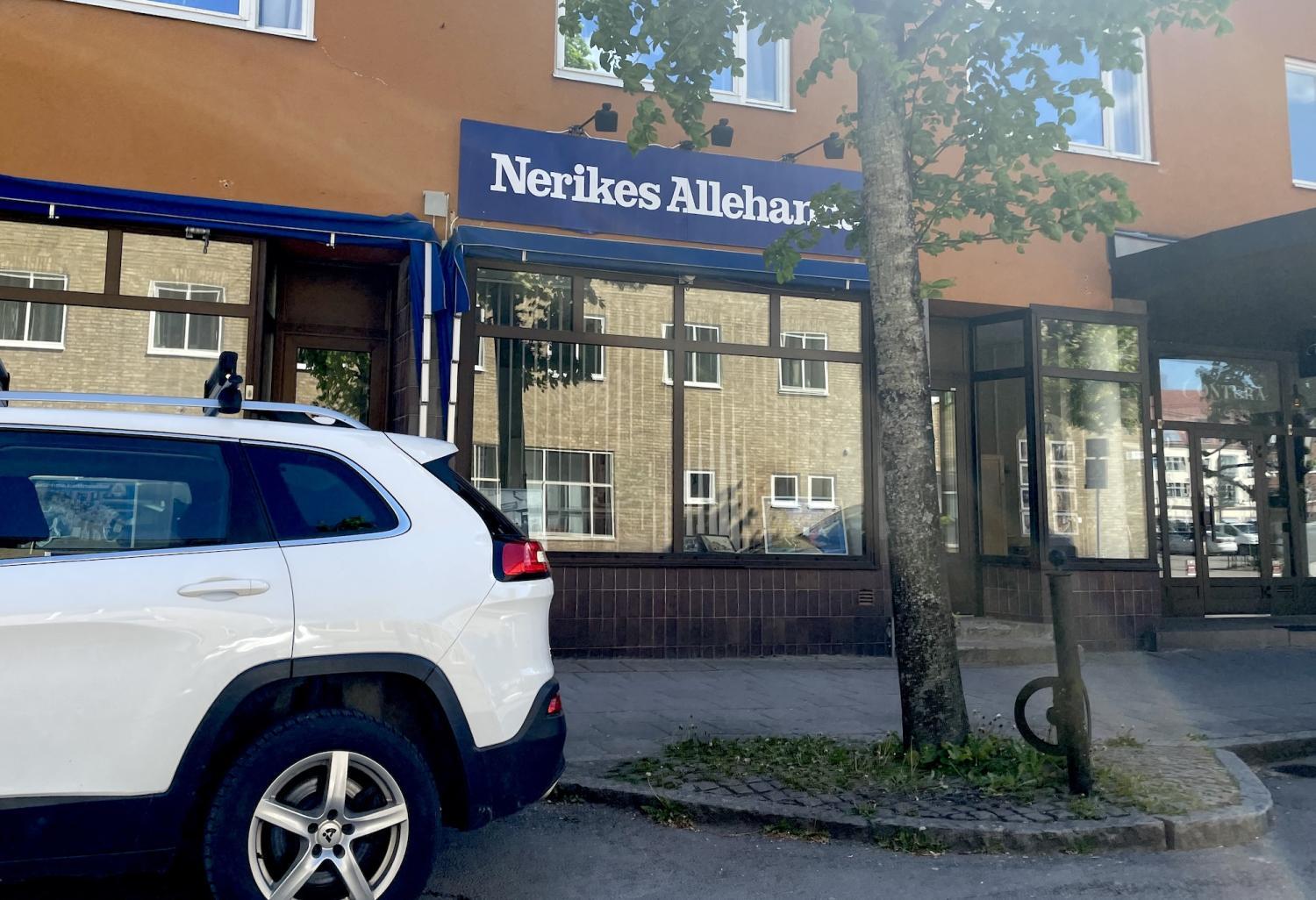 En vit SUV parkerad på en gata framför en byggnad med en skylt där det står 