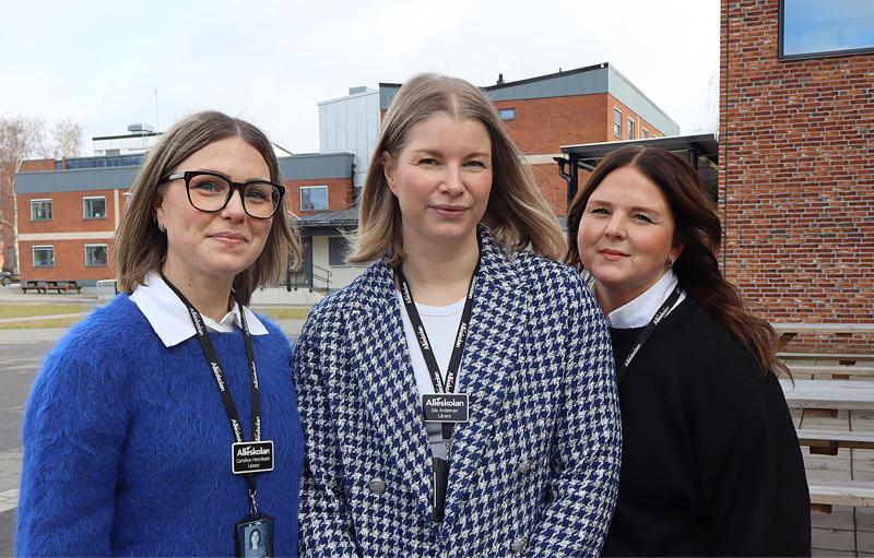 Tre kvinnor iförda affärskläder och anställningsbrickor står framför tegelbyggnader.