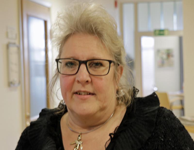 En kvinna i glasögon som står i en hall.