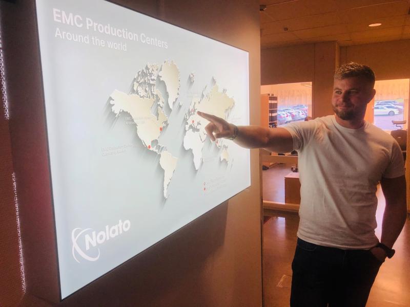 En man i vit t-shirt pekar på en världskarta på en skärm märkt 