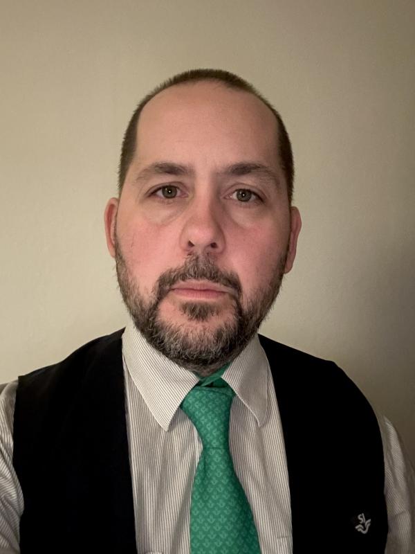 En man klädd i väst och grön slips.