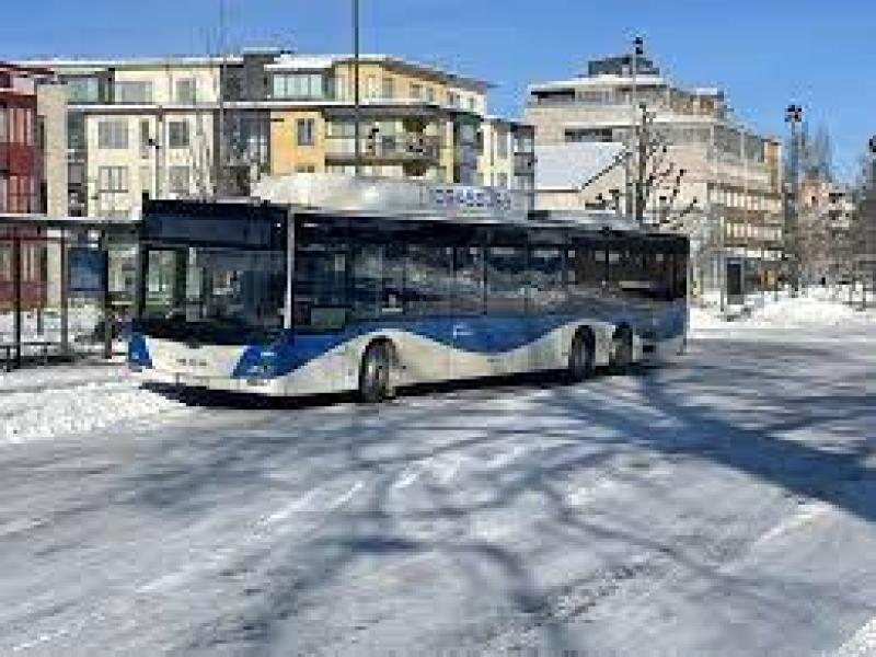En buss som kör nerför en snötäckt gata.