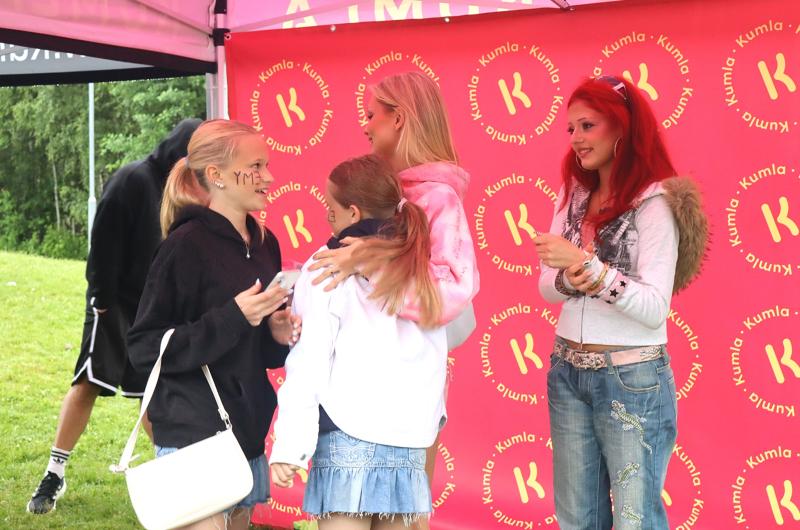 Fyra unga människor står och pratar under ett rosa tält med 