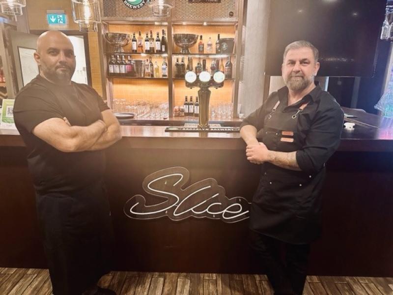 Två män i svarta uniformer står bakom en bar med en 