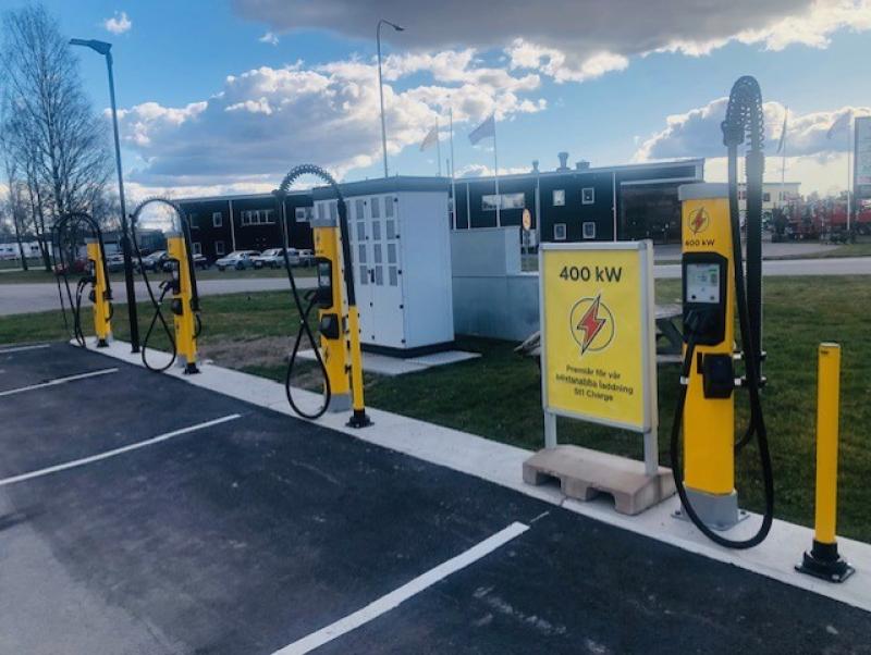 Laddstationer för elfordon med gul och svart design, märkta 400 kW, placerade på en asfalterad parkeringsplats under en molnig himmel.