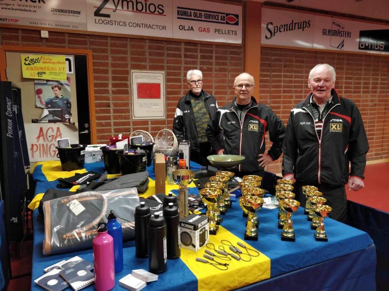 Tre män står framför ett bord med troféer.