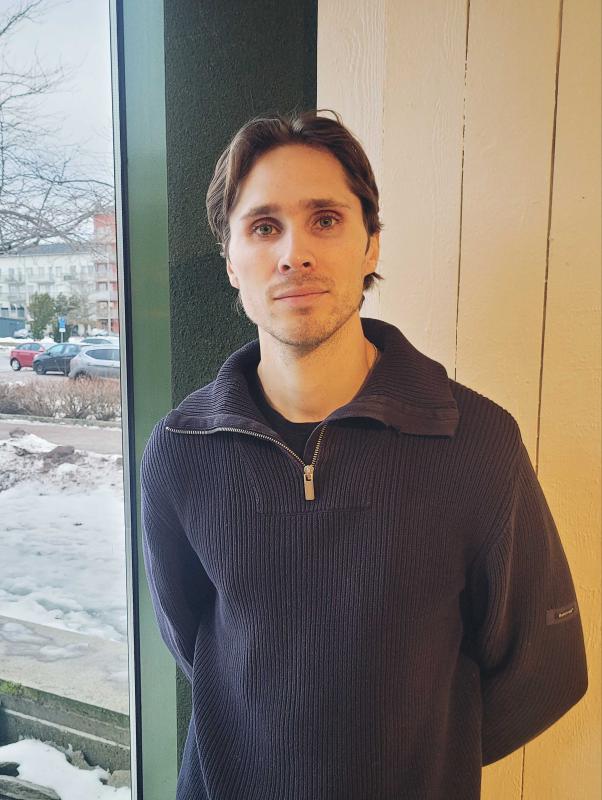 En man i en tröja som står framför ett fönster.