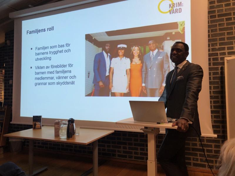 En man i kostym presenterar framför ett bildspel med titeln 