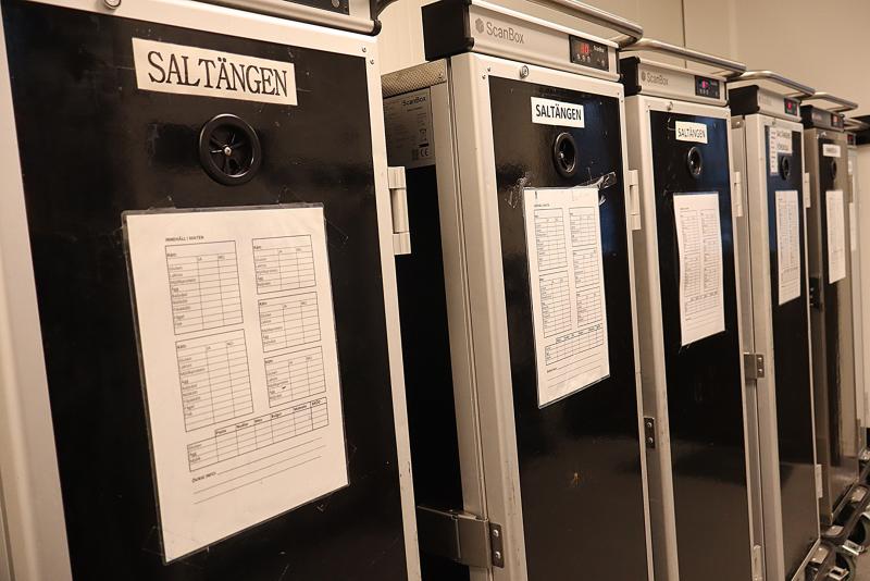 En rad matleveransvagnar med pappersscheman eller menyer på framsidan, märkta med 