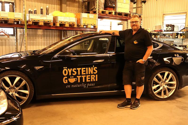 En man står bredvid en svart bil med texten 