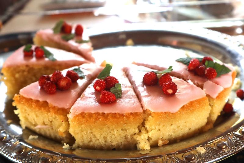 En tallrik med tårtskivor toppade med rosa glasyr, små röda bär och myntablad.